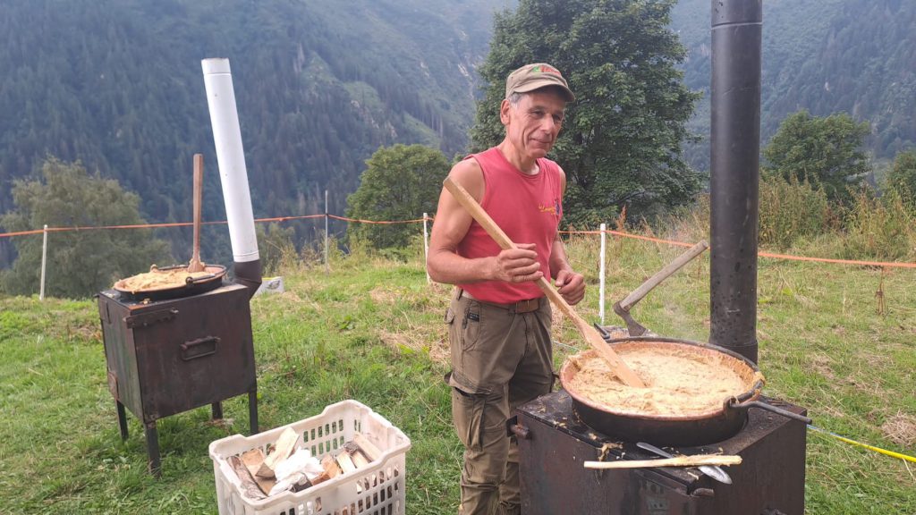 Un socio gira la polenta carbonera nel paiolo davanti alla malga