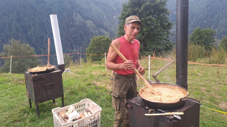 Un socio gira la polenta carbonera nel paiolo davanti alla malga