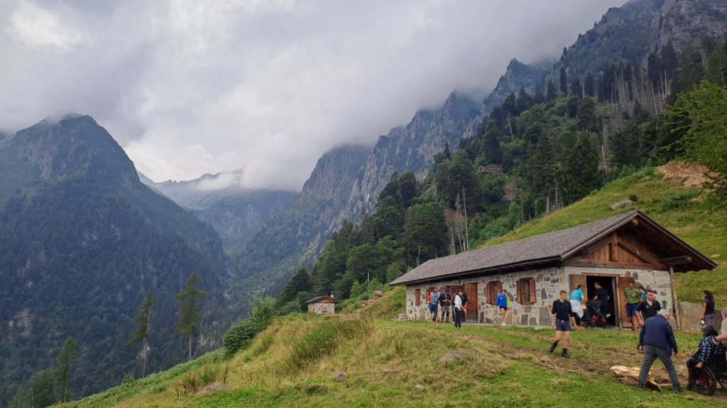 Malga Praino tra le montagne, con i soci riuniti davanti all’edificio