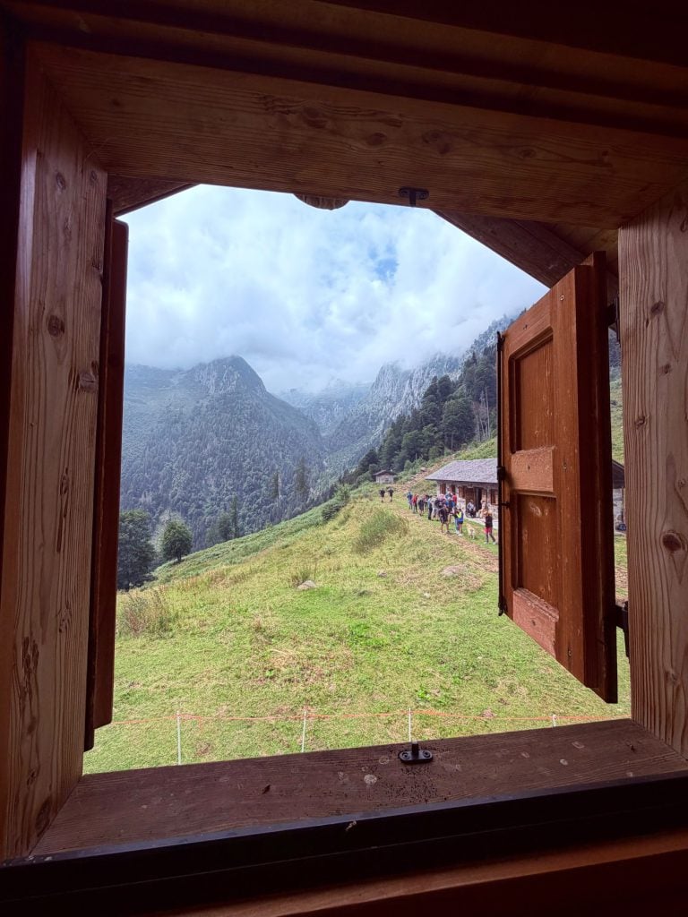 La valle vista dalla finestra in legno della malga