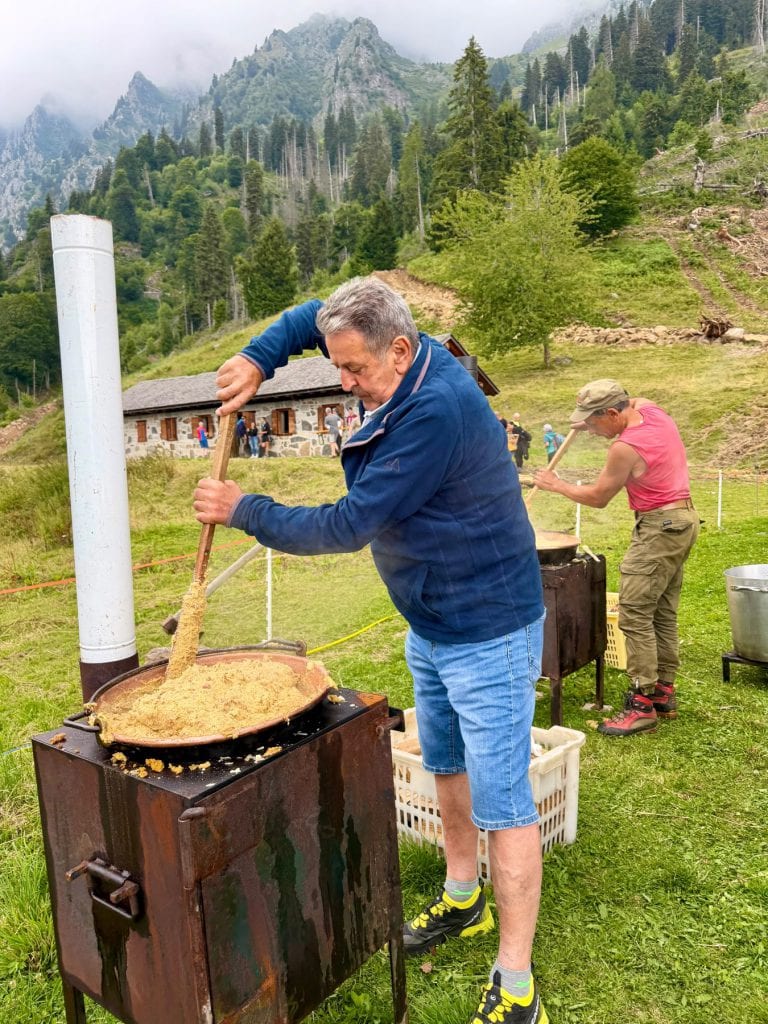 Due soci girano la polenta nei paioli davanti alla malga