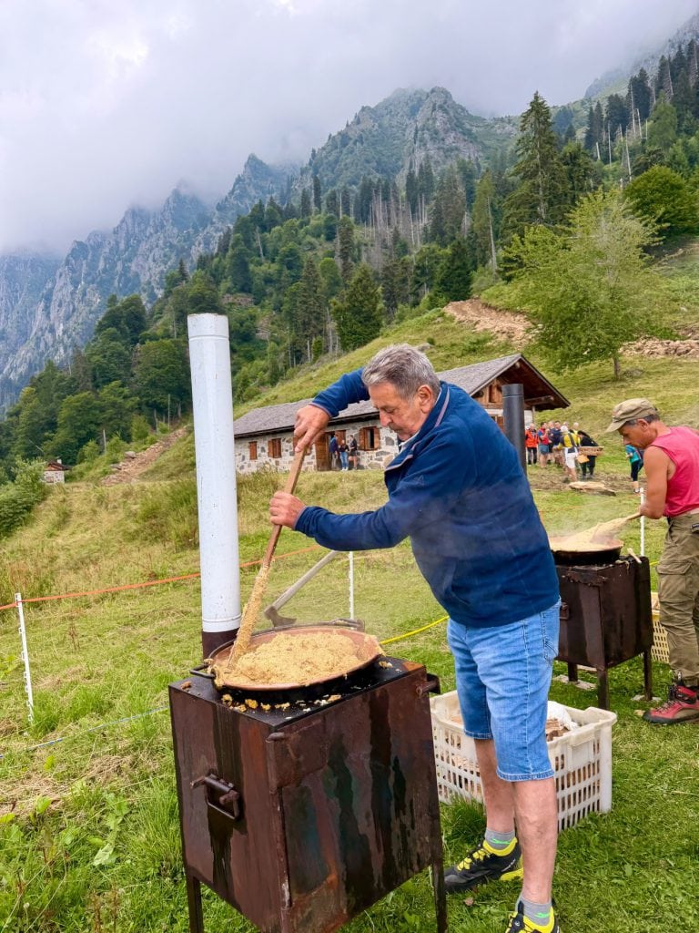 La polenta carbonera girata nel paiolo con la malga sullo sfondo